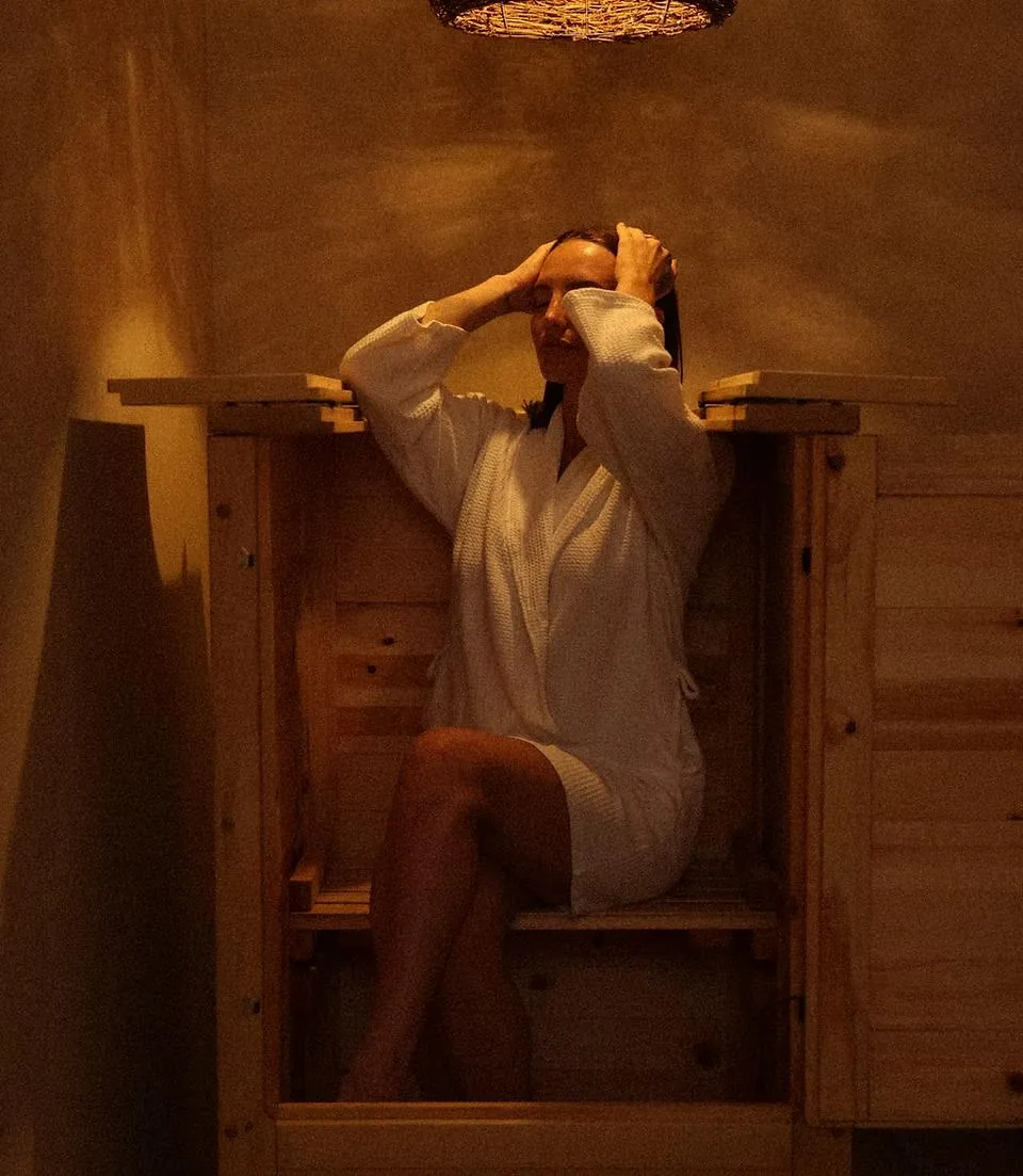 Client in a white robe relaxing in the herbal cedar steam sauna in the LIMFAERA private room