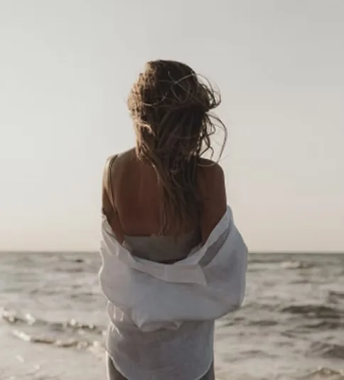 Woman in a white shirt looking out at the sea