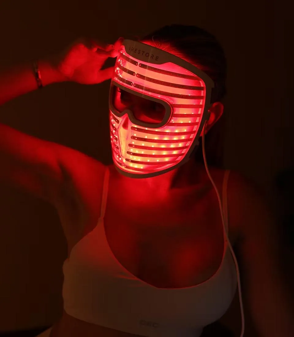Client wearing an LED red light therapy mask in a dark studio at LIMFAERA in Beverly Hills