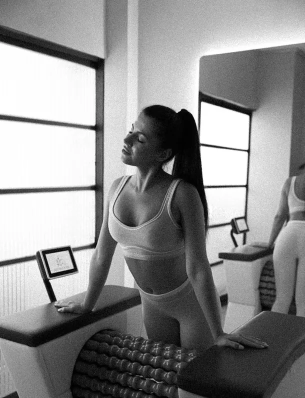 Black-and-white photo of a woman in activewear leaning on a body roller machine