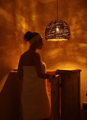 Woman in a white towel beside the herbal sauna barrel in the LIMFAERA private studio room